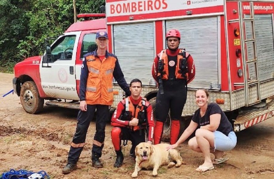Bombeiros militares posam ao lado de uma moradora e de um cachorro resgatado, em frente a uma viatura do Corpo de Bombeiros, em Conceição do Castelo.