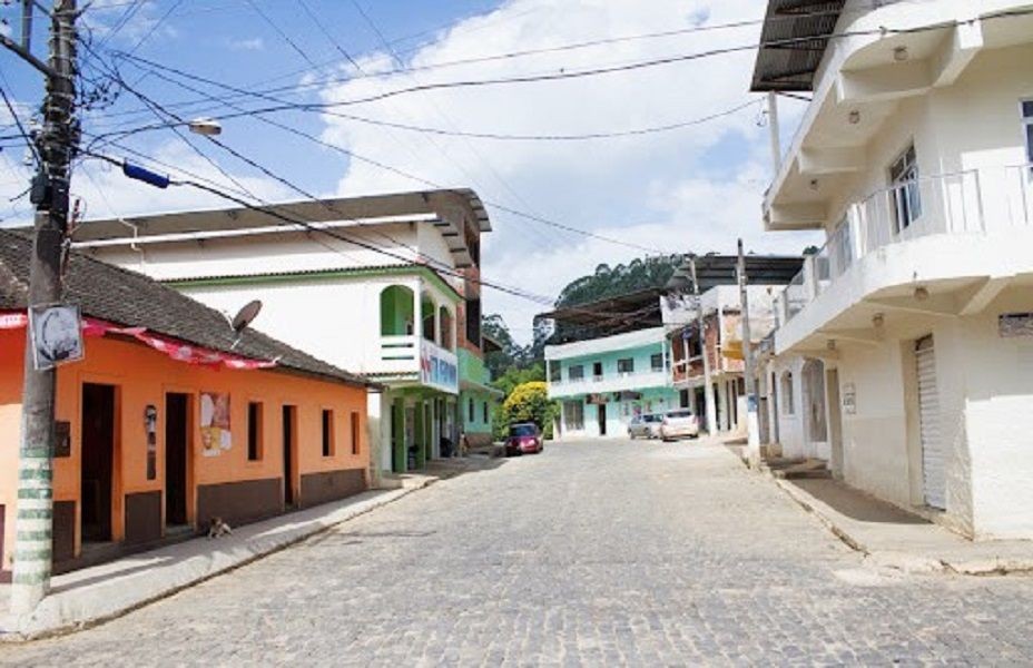 Vista de uma rua do distrito de Santa Marta, em Ibitirama, com casas coloridas, via calçada e infraestrutura urbana da região que será beneficiada por obra de reurbanização.