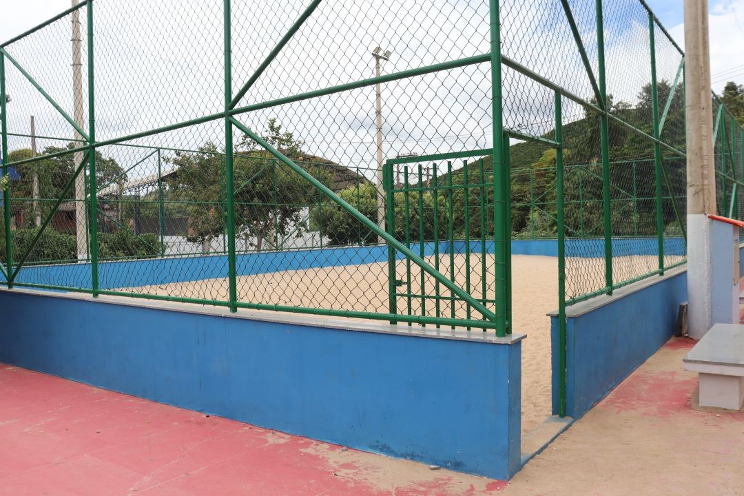 Quadra de areia no bairro Guanabara, em Iúna, onde serão realizadas as competições do Circuito de Verão, cercada por alambrado e localizada próxima à Escola Estadual Santíssima Trindade.