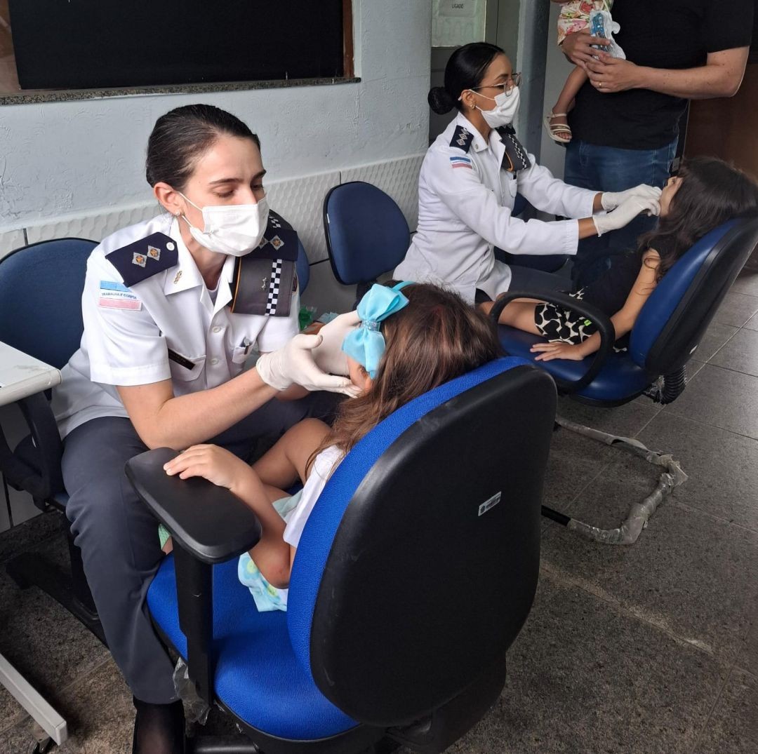 Dentista da Polícia Militar realiza avaliação odontológica em criança durante ação de saúde bucal no 3º BPM.
