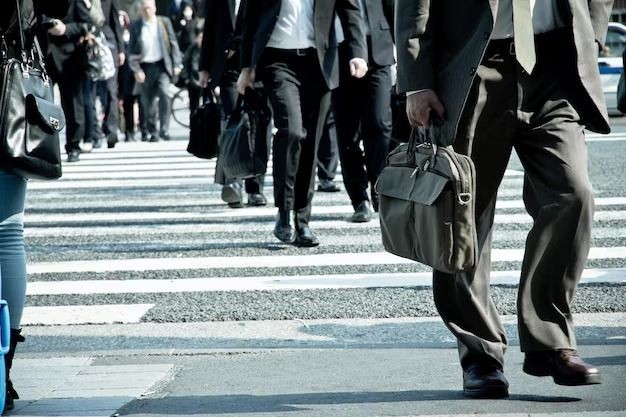 Pessoas atravessando faixa de pedestres em área urbana, representando trabalhadores em deslocamento e o debate sobre jornada de trabalho no Brasil.