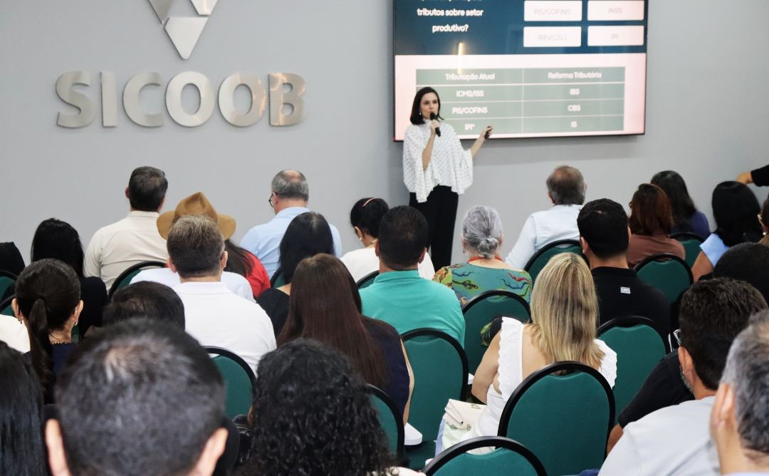 Auditório do Sicoob Iúna lotado durante palestra sobre Reforma Tributária, com a advogada Diane Espíndola apresentando os impactos do novo sistema tributário a empresários, produtores rurais e contadores da região do Caparaó.