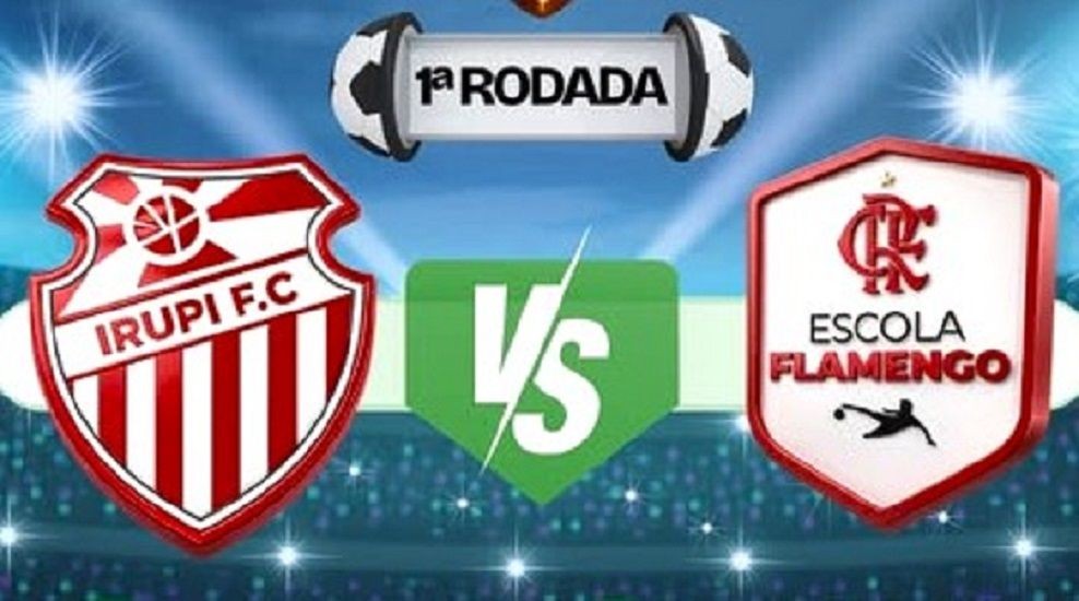 Imagem dos escudos do Irupi FC e da Escola Flamengo sobre um fundo azul com degradê e luzes faiscando, que lembra um estádio com arquibancada iluminada com a sigla VS entre os dois escudos e, acima, uma bola aberta que abre uma faixa onde está escrito 1ª rodada.
