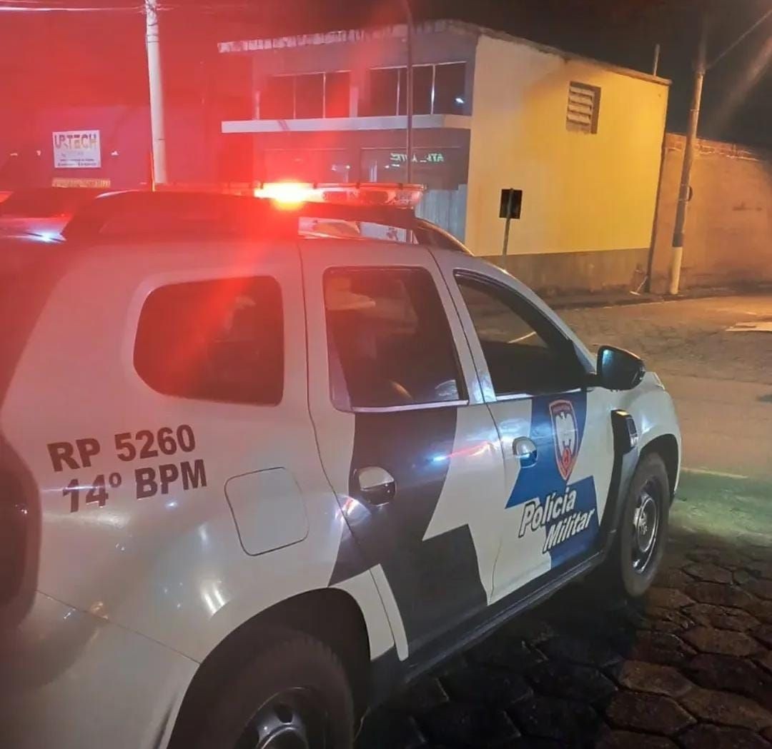 Viatura da Polícia Militar com giroflex ligado durante atendimento de ocorrência noturna em área urbana.