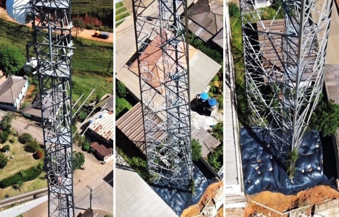 Imagens aéreas mostram uma torre de telefonia metálica instalada em área urbana, próxima a casas, com destaque para a base da estrutura onde há indícios de intervenção e possível risco estrutural.