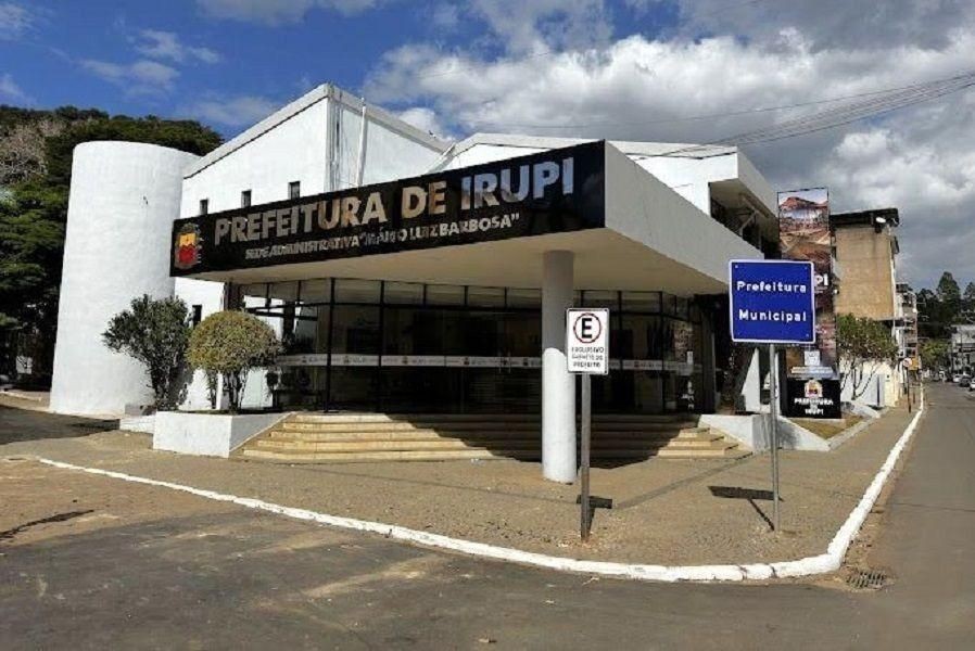 Fachada da Prefeitura de Irupi, prédio branco com entrada principal e placa de identificação, localizada em área urbana do município.