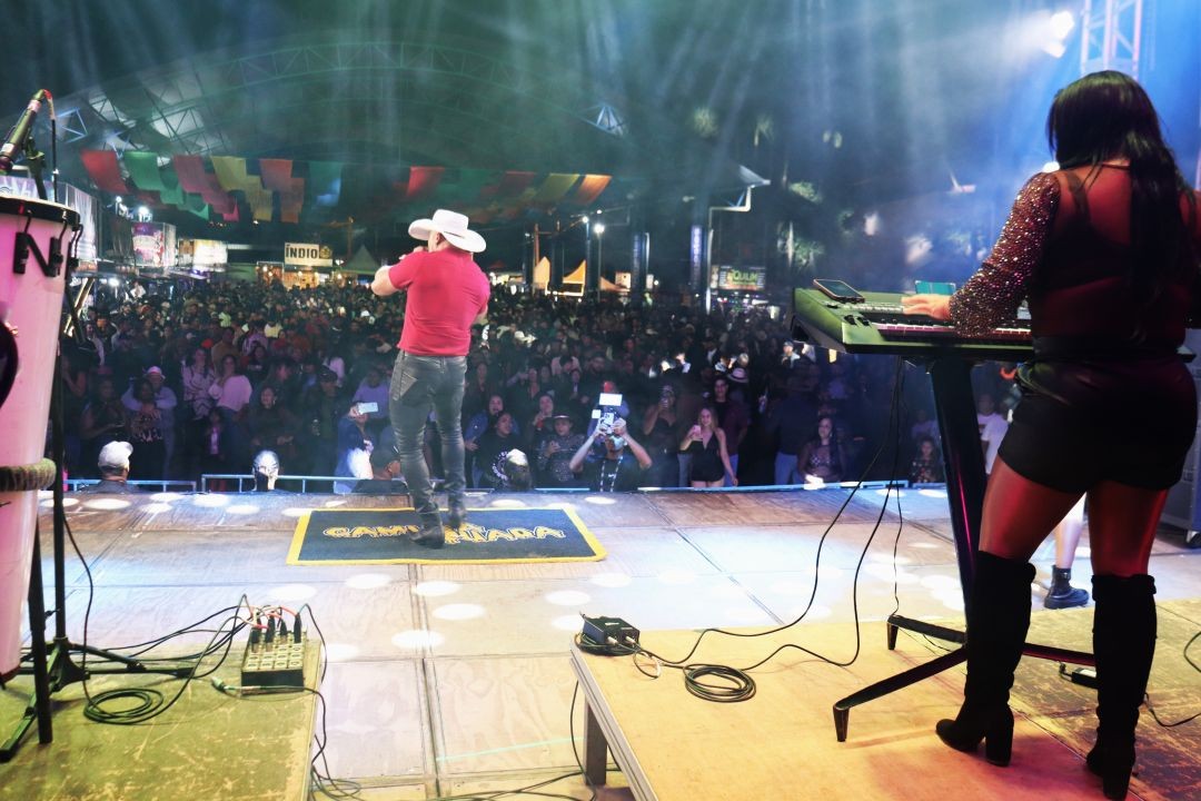 Cantor se apresenta no palco durante show da Expoagro de Patrimônio da Penha, com grande público reunido em frente ao palco e iluminação de evento noturno.