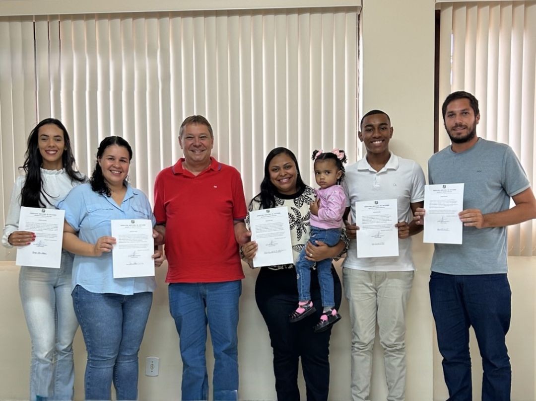 Grupo de novos servidores municipais de Ibitirama posa com documentos de posse durante cerimônia oficial.