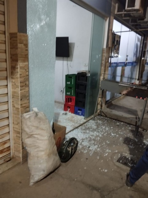 Vidro de estabelecimento estilhaçado após disparos de arma de fogo em bar no Centro de Dores do Rio Preto