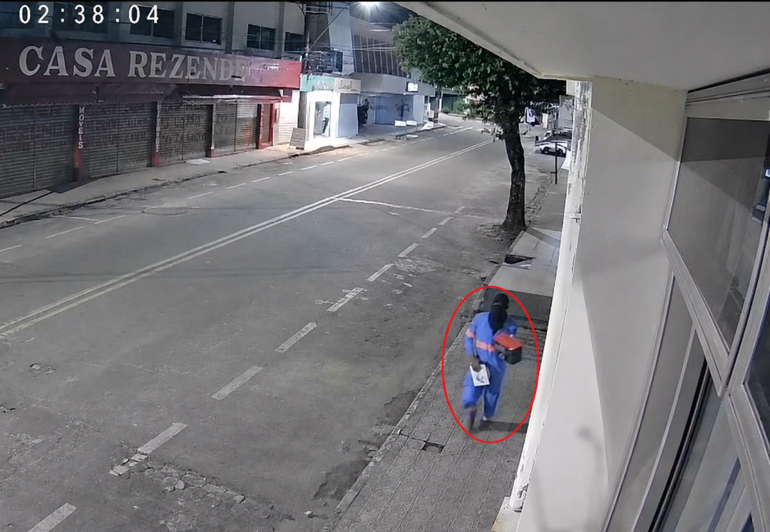 Imagem de câmera de segurança mostra suspeito circulado em vermelho caminhando na calçada após furto em loja de celulares no Centro de Alegre durante a madrugada.