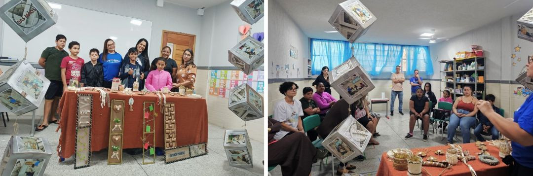 Grupo de alunos, professoras e participantes reunidos em sala de aula durante exposição de artesanato do projeto “O Amor na Palma das Mãos”, em Iúna, os participantes acompanharam apresentação e roda de conversa em sala decorada com peças artesanais e fotografias suspensas durante atividade cultural em Iúna.