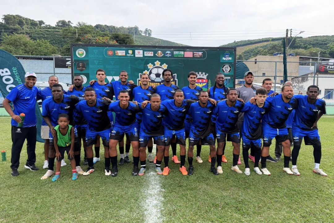 Foto posada do time do Jacá. Cerca de vinte jogadores e integrantes da comissão técnica usam uniforme azul com detalhes pretos e meias pretas. Uma criança pequena vestindo colete verde está posicionada na frente, agachada entre os atletas no gramado. Ao fundo, uma lona verde exibe as marcas dos patrocinadores e o escudo da competição.