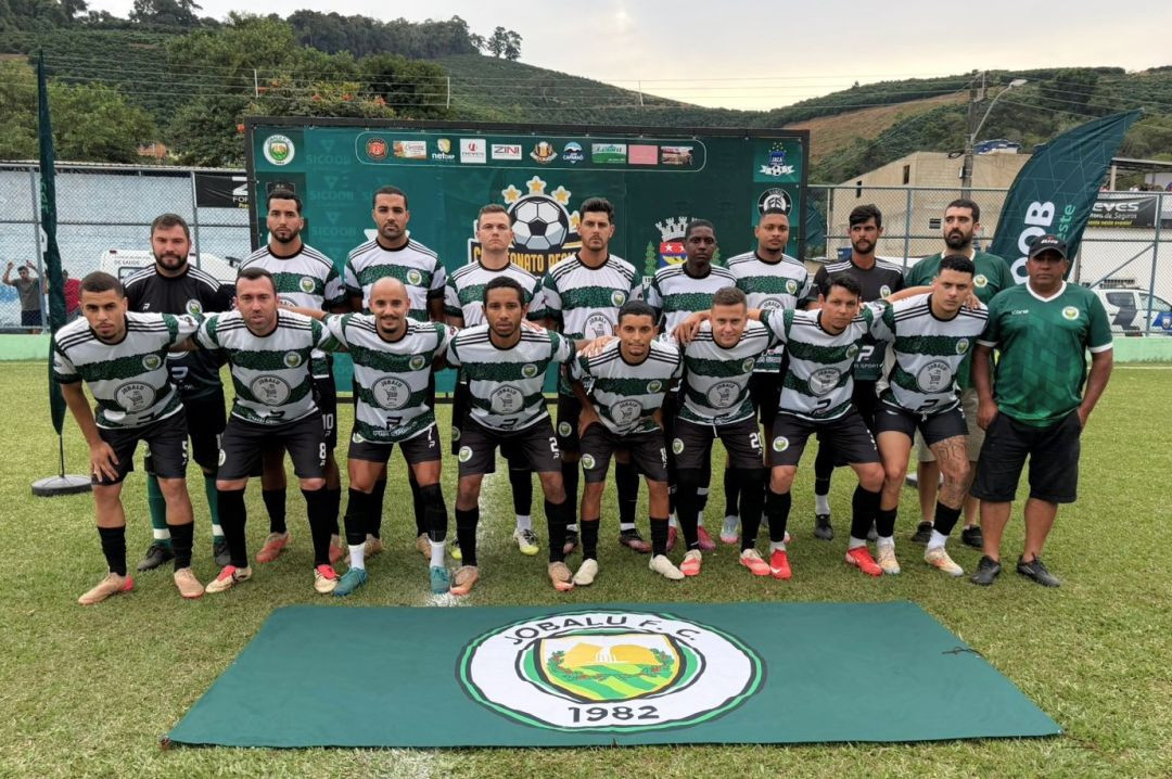 Foto oficial do time do Jobalu F.C. Os atletas vestem camisa com listras horizontais verdes, pretas e brancas, calções pretos e meiões pretos. Na frente do grupo, no chão, estende-se uma bandeira verde com o escudo redondo da equipe e o ano de fundação, 1982. Ao fundo, está a estrutura de publicidade do torneio.