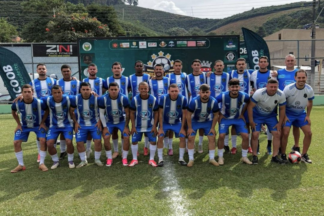 Foto posada da equipe do Santa Clara. Os atletas estão perfilados no gramado vestindo camisas listradas verticalmente em azul e branco, calções azuis e meiões brancos. Dois integrantes da comissão técnica aparecem na ponta direita usando camisas brancas e calções azuis, um deles segura uma bola de futebol no chão.