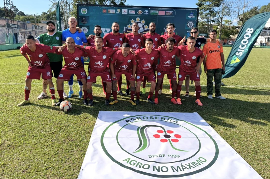 Foto oficial da equipe do Agroserra reunida no gramado. Os jogadores vestem uniformes na cor grená com detalhes brancos e a marca Ajinomoto estampada. O goleiro veste uniforme azul. À frente do time, uma lona branca está estendida no gramado com o logotipo redondo da Agroserra contendo flores vermelhas e a frase 