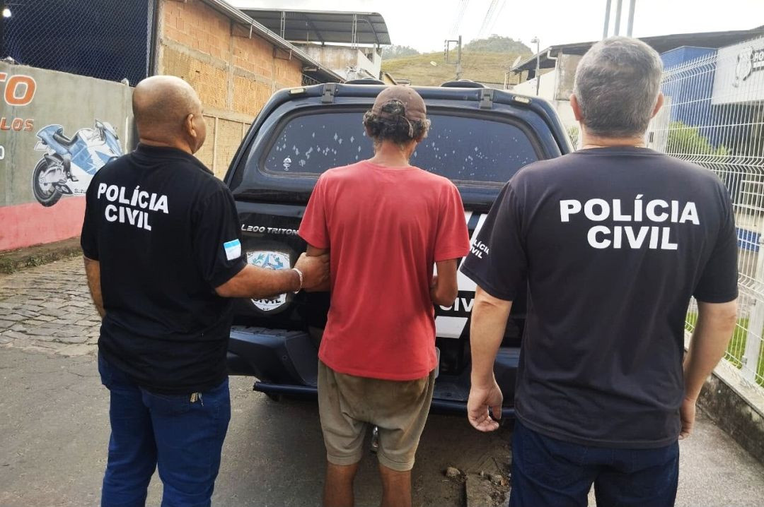 Foto de costas mostra dois policiais civis com camisas pretas escritas 