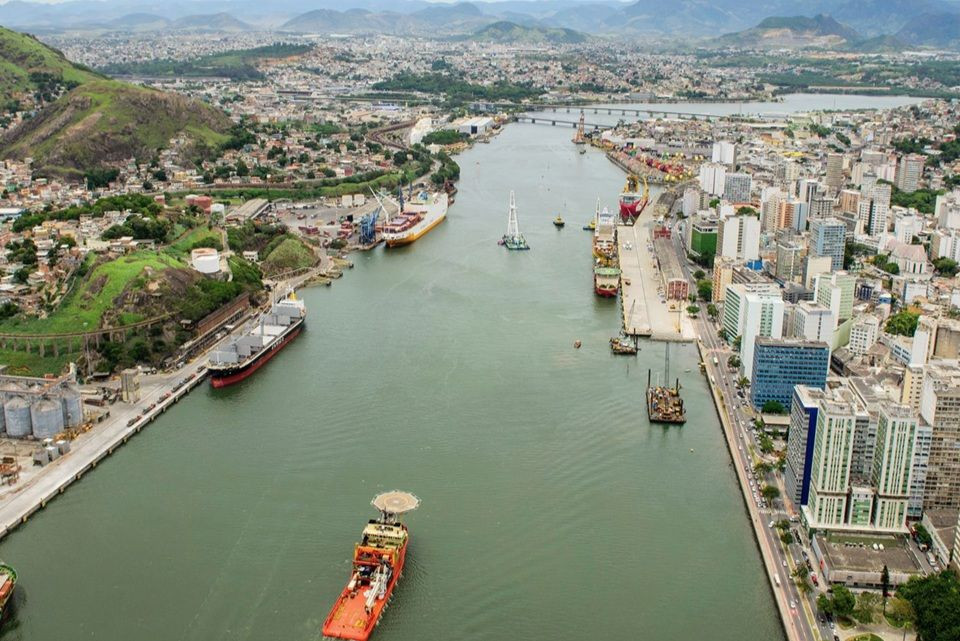Vista aérea do Canal de Vitória mostrando navios cargueiros atracados no porto e a paisagem urbana do centro da cidade.