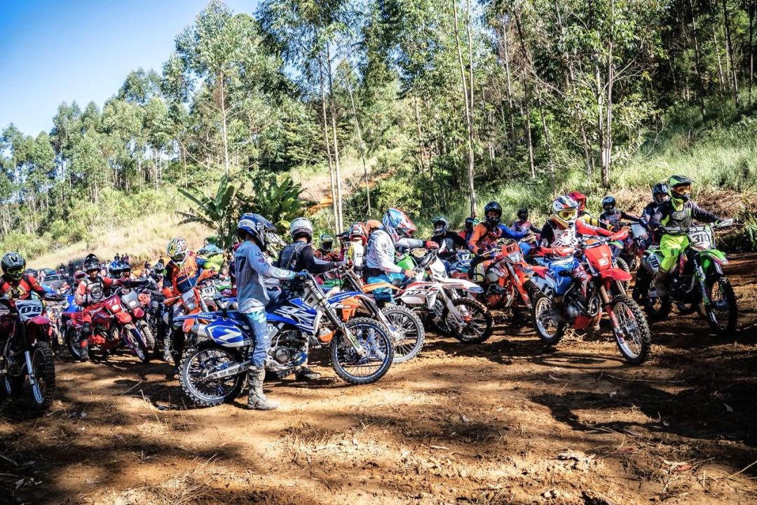 Pilotos reunidos com motocicletas off-road antes da largada do Encontro de Trilheiros, em área cercada por vegetação no município de Muniz Freire.