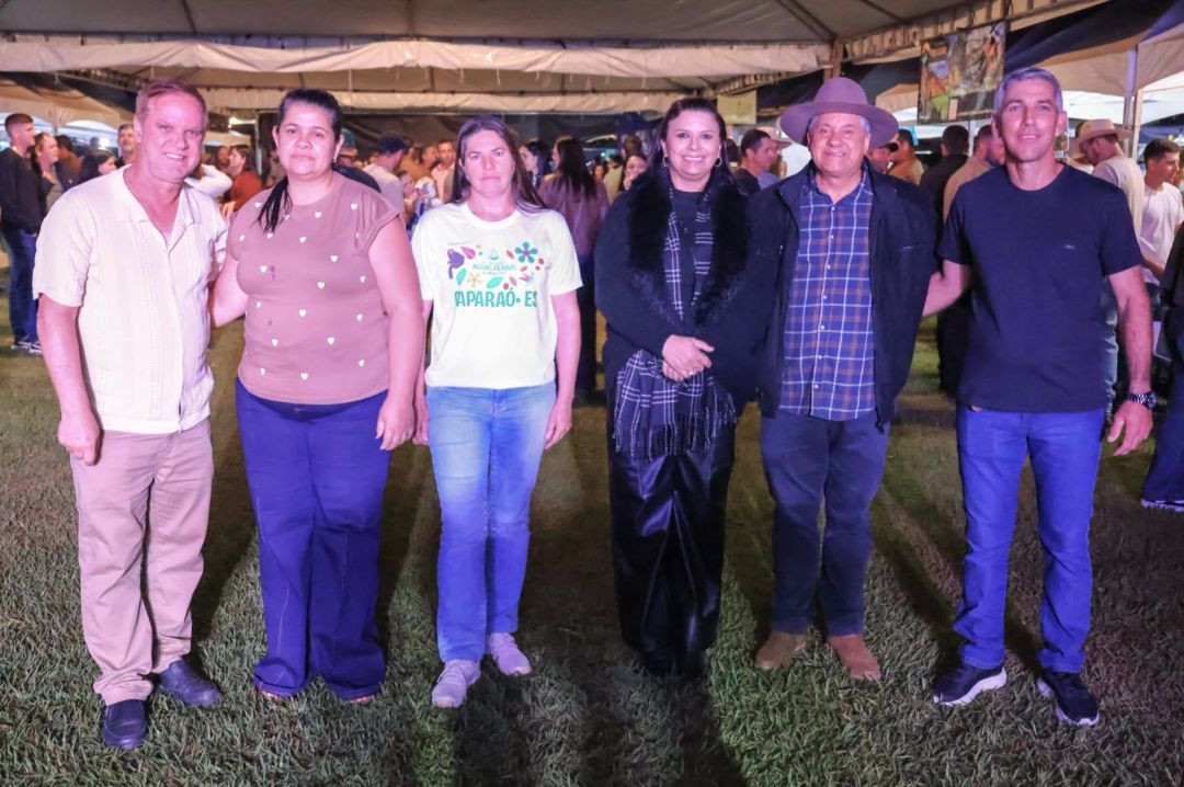 Seis pessoas, entre organizadores e representantes locais, posicionadas lado a lado em pé sobre o gramado do evento.